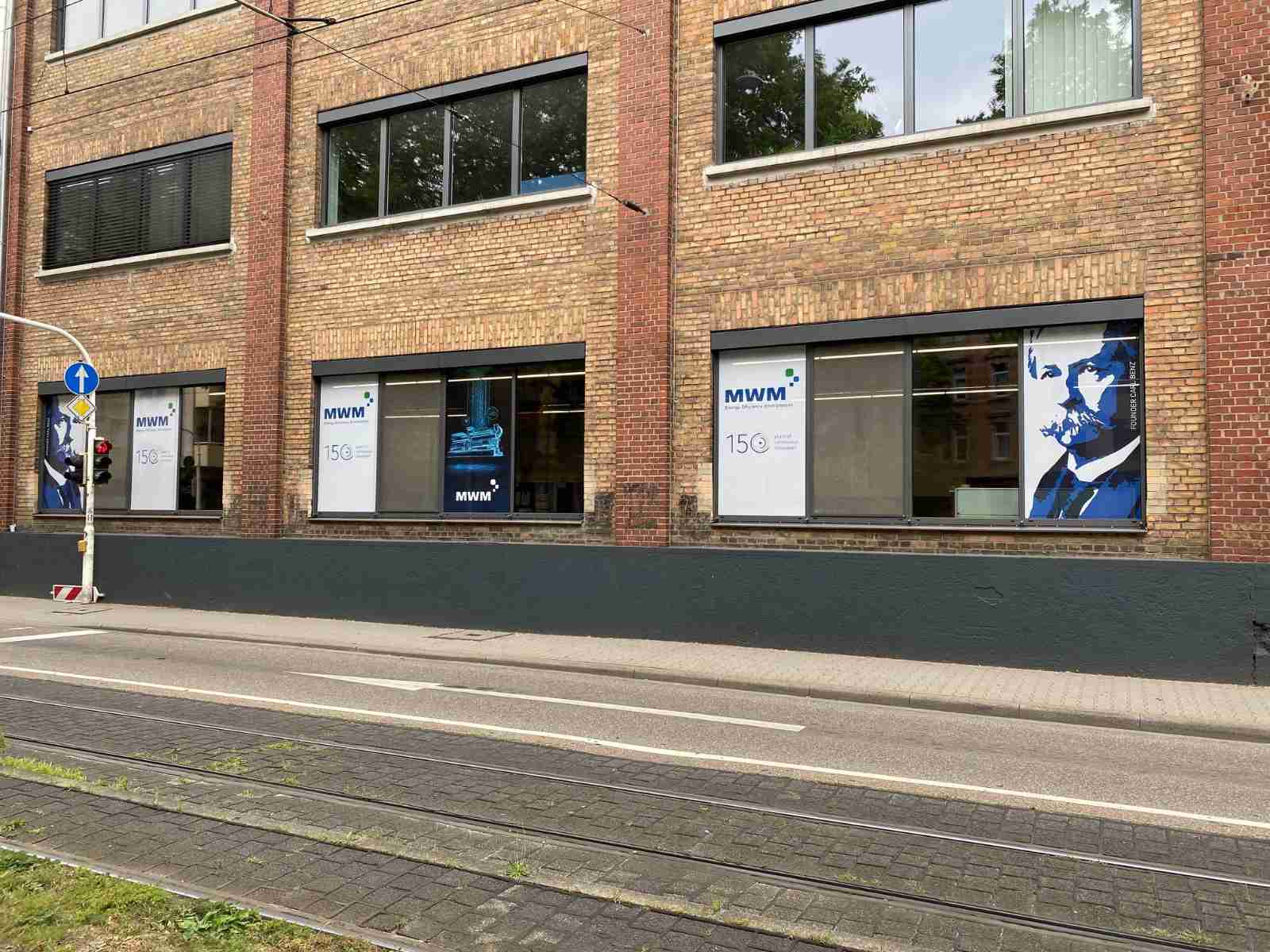 Some of the windows facing Waldhofstrasse and Carl-Benz-Strasse showing company founder Carl Benz and the MWM TCG 3016 gas engine